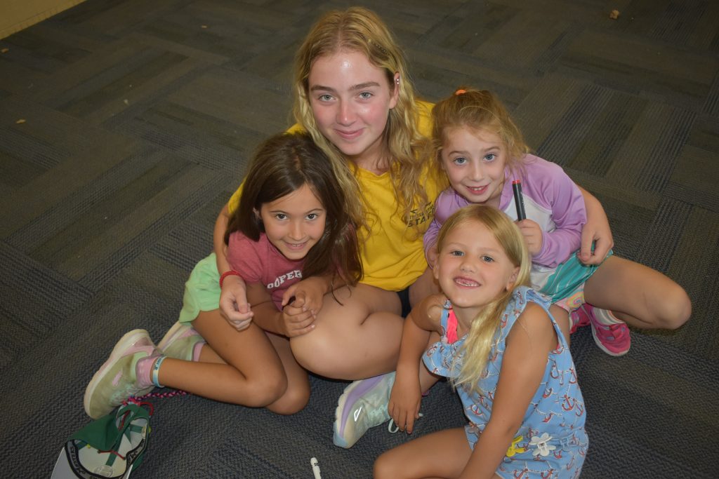 a young counselor hugging a group of young girls during summer day camp programs